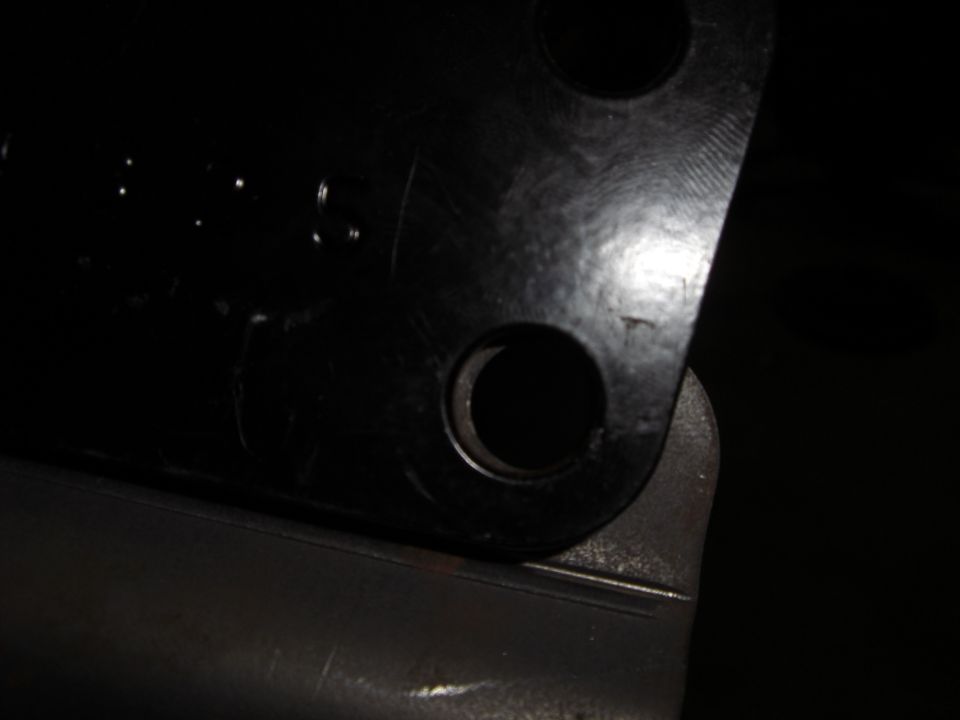 Dark close-up of a black steel bracket corner with two drilled bolt holes