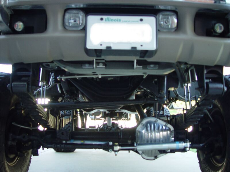 Underside front view of tan Ford Excursion showing suspension, chrome sway bar and dual steering stabilizers