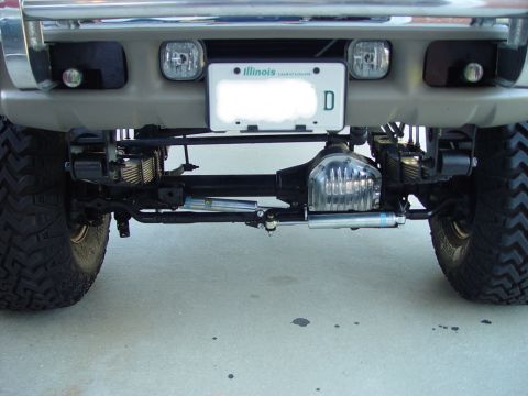 2001 Ford Excursion - Close-up view of the front suspension and axle assembly of a heavily modified truck.