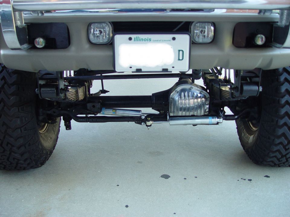 Underside front view of lifted truck with chrome diff cover, dual steering stabilizers and off-road tires