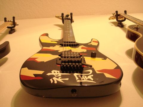 1979 Chevrolet C/K Pickup - An electric guitar with a camouflage paint job and Japanese characters is displayed on a wall mount.
