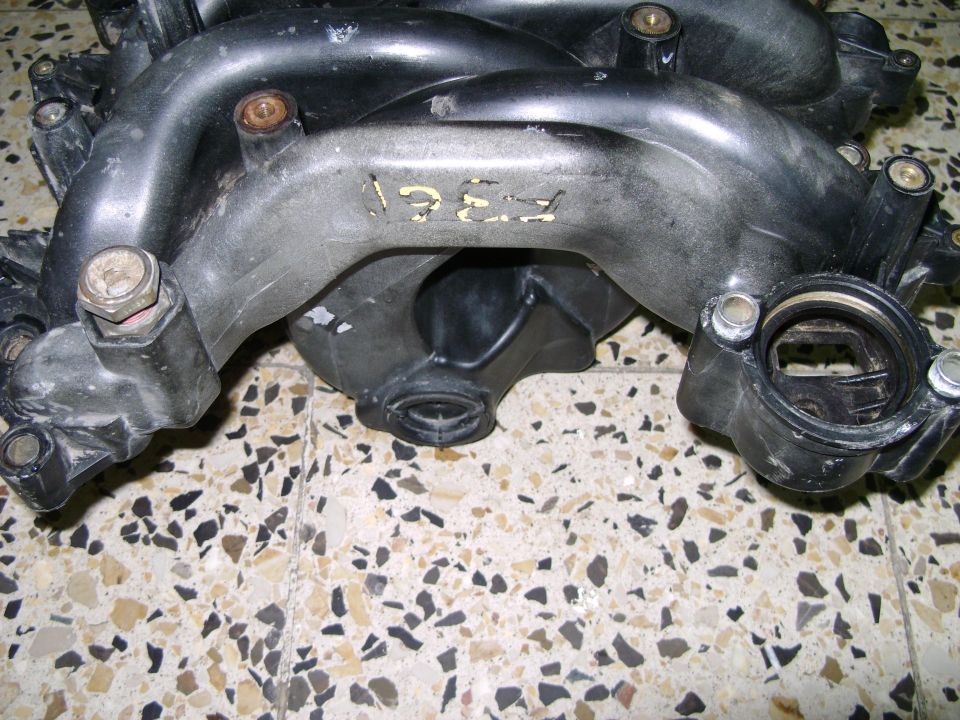 Plastic intake manifold with yellow markings that appear to say '1987'