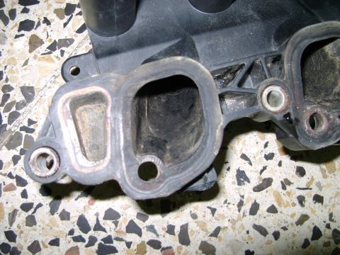 1998 Ford Crown Victoria - A close-up view of a used plastic intake manifold part, showing wear and gasket residue.
