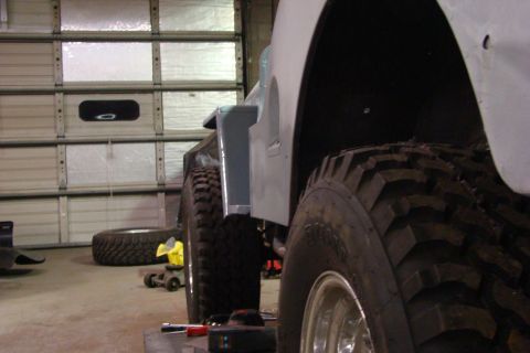 1948 Jeep Wrangler - A Jeep CJ-series is shown from the side, large tires and a gray primer body, in what appears to be a garage or workshop.