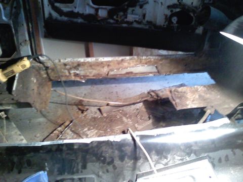 1969 Ford Mustang - A power tool is used to address severe rust damage on a car's floor pan during a restoration project.