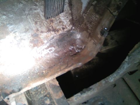 1969 Ford Mustang - The undercarriage of the vehicle shows significant rust and damage, with a dark opening visible below.