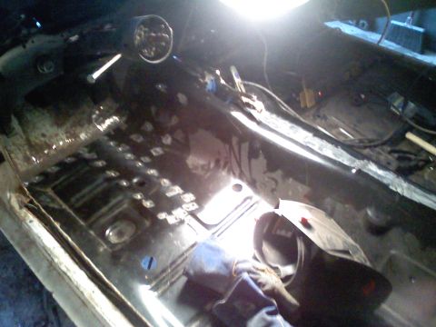 1969 Ford Mustang - The interior of a car is shown during a restoration project, with the floor stripped to bare metal and dashboard components visible.
