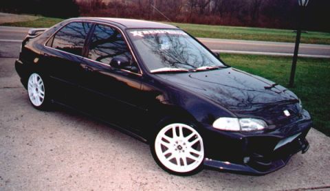 1999 Ford Taurus - Front three-quarter view of a lowered black Honda Civic four-door sedan parked on a concrete driveway beside a lawn. It wears white multi-s…