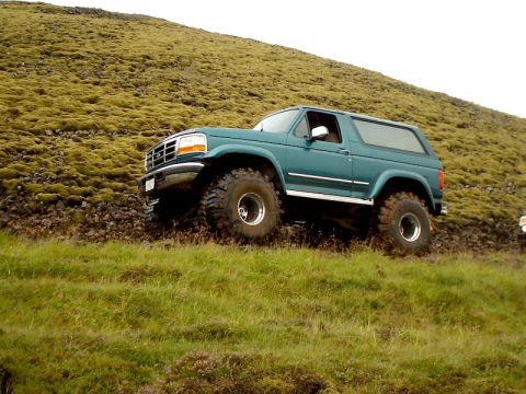1996 Ford Bronco - Teal Ford Bronco navigates a challenging off-road terrain with steep inclines and loose ground.