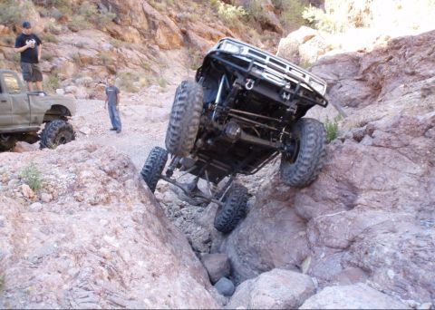 1986 Toyota Hilux - Off-road trucks navigate challenging rocky terrain in a desert environment.