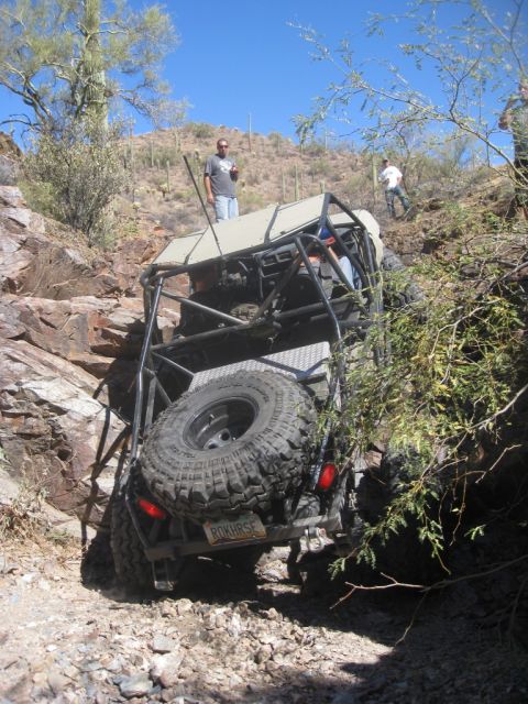 1986 Toyota Hilux - A custom off-road buggy navigates a steep, rocky incline in a desert environment.