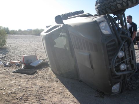 1986 Toyota Hilux - An overturned off-road vehicle lies on its side in a desolate, dry environment.
