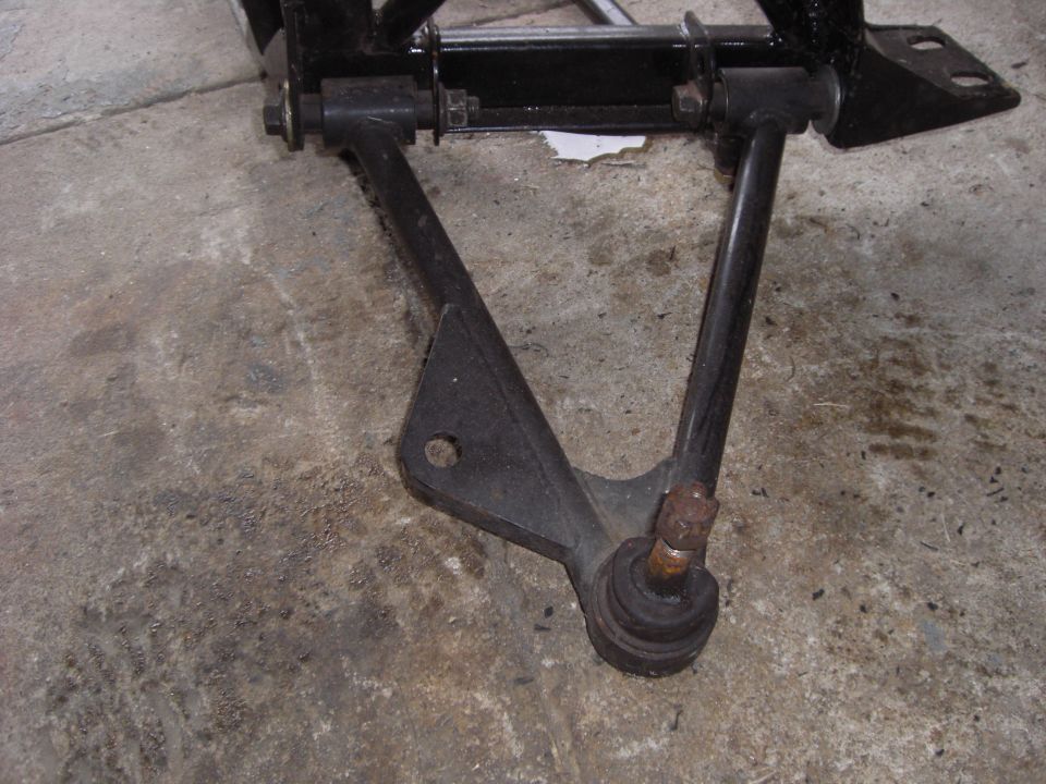 Removed black A-arm control arm with ball joint and pivot bushings on shop floor