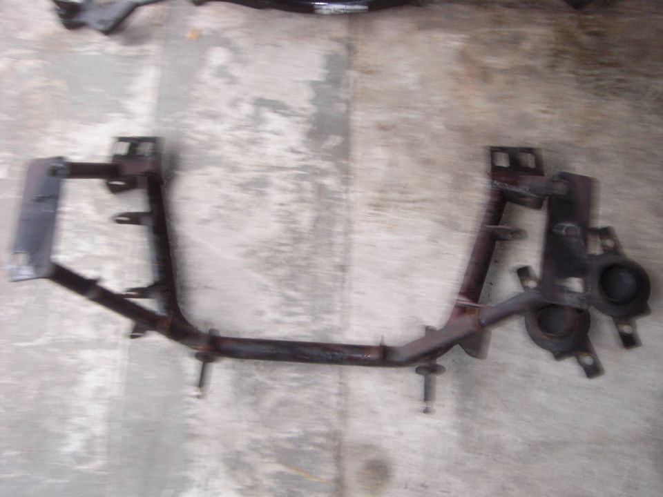 Rusty removed steel crossmember with mounting tabs and studs on concrete floor