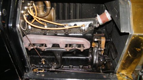 1915 Ford Model T - The engine compartment of a 1915 Ford Model T shows its black engine block and brass exhaust manifold.