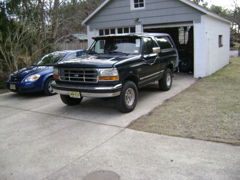 1994 Ford Bronco - 1994 Ford Bronco parked in driveway with a blue car beside it and a garage behind.
