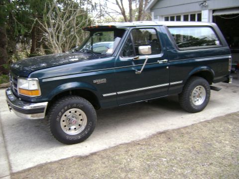 1994 Ford Bronco - This Ford Bronco is parked in front of a garage with trees in the background.