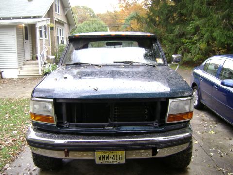 1994 Ford Bronco - Front view of a dark green Ford truck, possibly a 1992 model, with its grille removed.