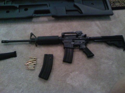 1989 Ford Bronco - An assault rifle, magazine, and ammunition are laid out on a carpeted surface next to a black case.