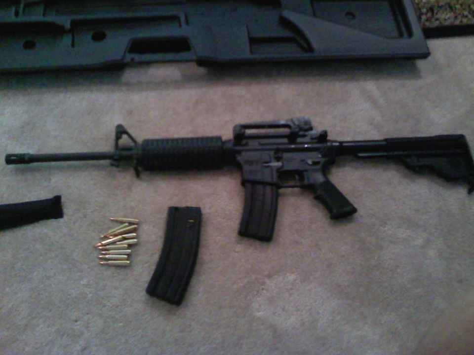 Assault rifle with magazine and loose cartridges on carpet, with a black case in the background