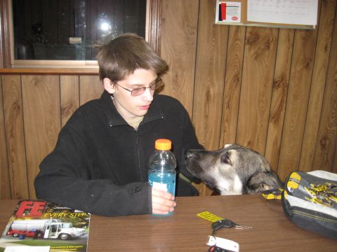 1978 Ford Bronco - A teenager and a dog share a table with a drink and a magazine, set against wood-paneled walls.