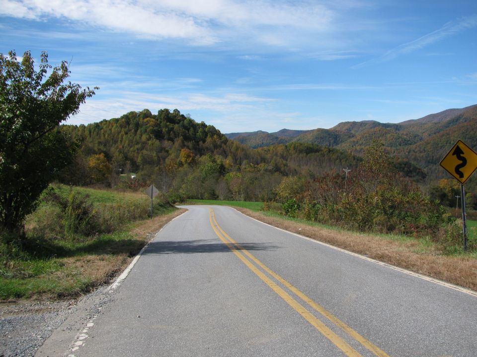 Winding mountain road with a yellow curve warning sign
