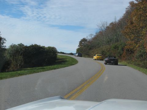 1985 Ford LTD Crown Victoria - A group of cars travel along a scenic route during autumn.