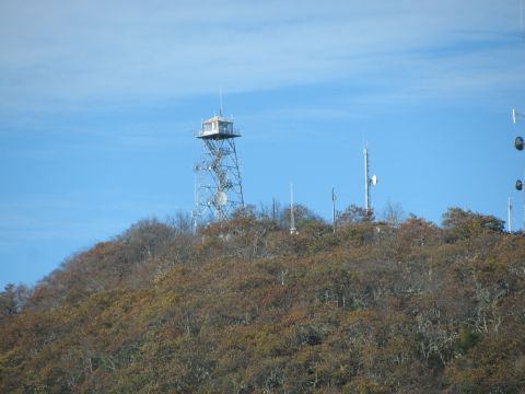 1985 Ford LTD Crown Victoria - Multiple communication towers and an observation tower stand atop a hill covered in autumn foliage.