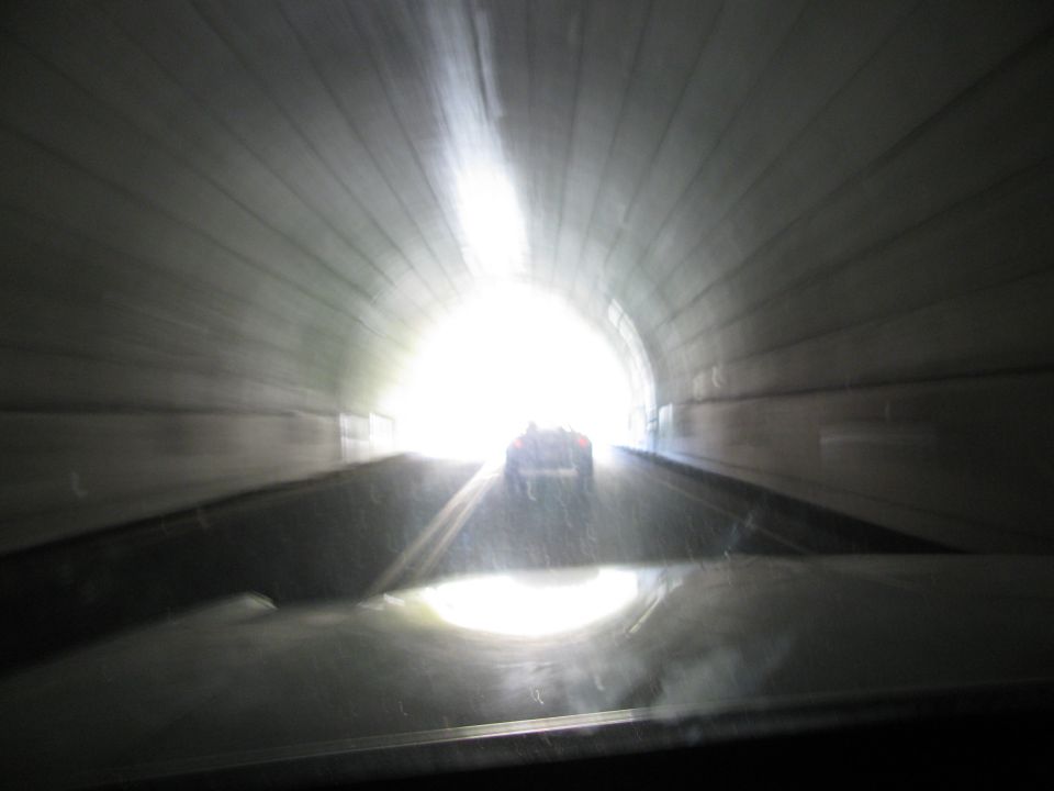 Rear view of a car driving through a tunnel towards bright light