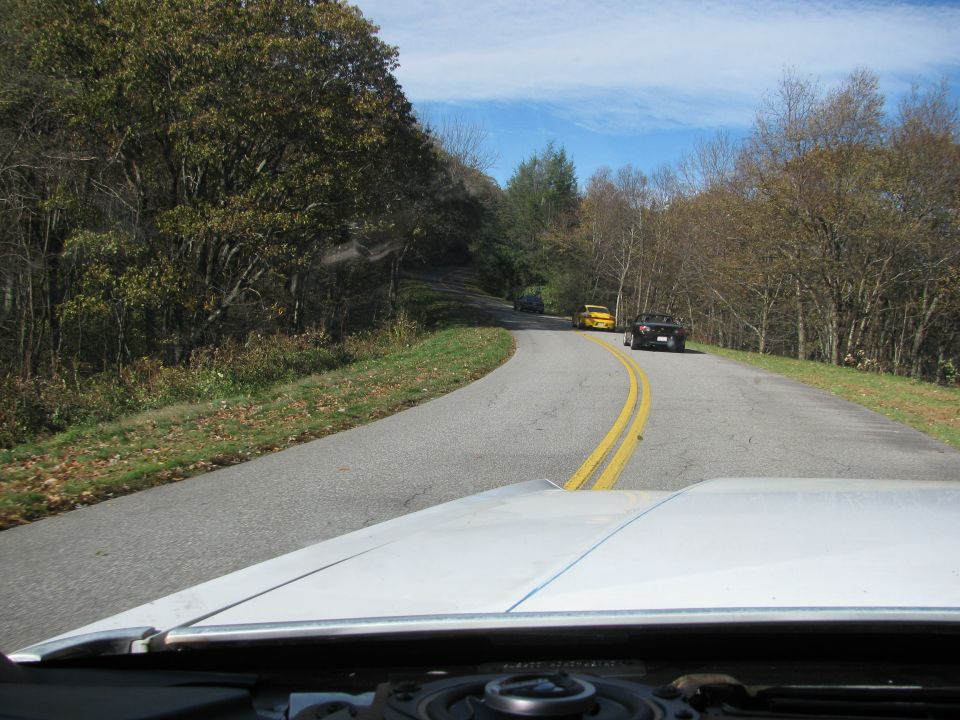 View from inside a car looking at a winding road with three other cars ahead