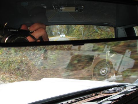 1985 Ford LTD Crown Victoria - A white car is seen on a road, viewed from the interior of another vehicle.