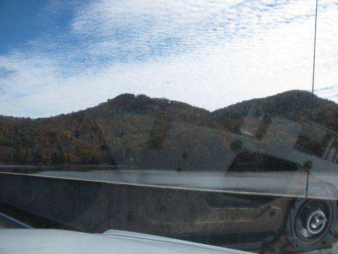 1985 Ford LTD Crown Victoria - View from inside a vehicle shows a lake and hills, with reflections on the windshield.