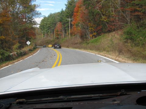 1985 Ford LTD Crown Victoria - Two cars are visible on a road during autumn, seen from the perspective of another vehicle.