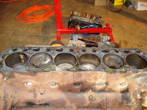 1991 Ford Bronco - Engine block with six cylinders exposed, resting on a red engine stand in a workshop.