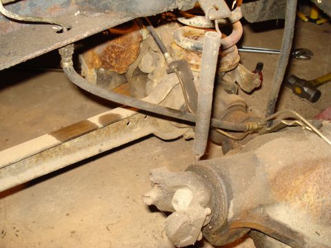 1991 Ford Bronco - Close-up view of the rear axle and suspension components, including brake lines and a coil spring.