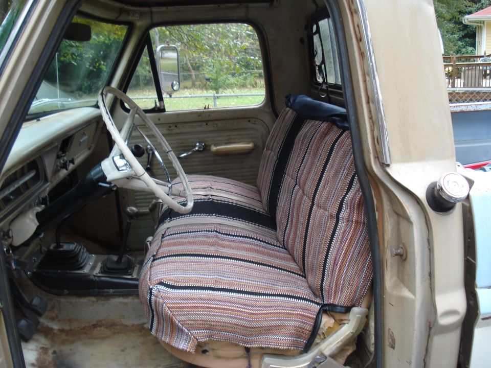 Tan 1967 Ford F-250 interior with striped seat covers, white steering wheel, and floor shifter
