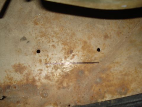 1967 Ford F-250 - A close-up view of a rusted metal panel, possibly from a vehicle's interior, showing two small holes and a horizontal line.