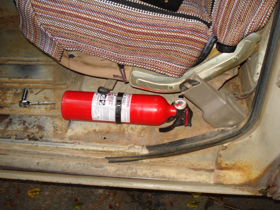 Fire extinguisher and socket wrench on the floor of a vehicle interior