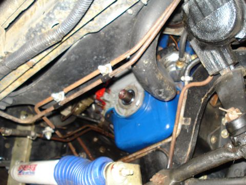 1984 Ford Bronco - Underside view of engine components, including a bright blue oil pan and numerous fuel or brake lines.