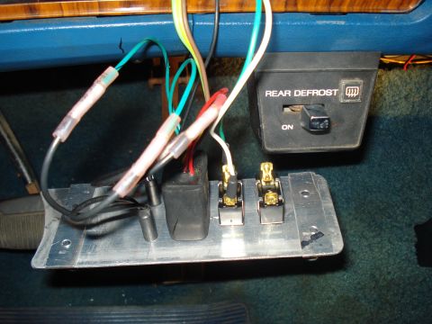 1984 Ford Bronco - Custom under-dash switch panel made from a bent aluminum plate holding two toggle switches with gold spade terminals and a black rocker, wi…