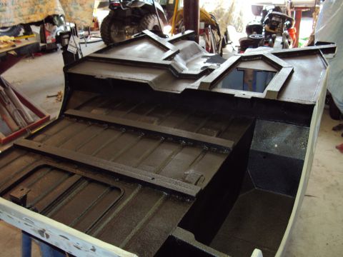 1948 Jeep Wrangler - The underside of a vehicle's body, likely undergoing restoration or repair, is shown in a garage setting.