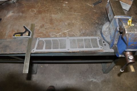 1996 Ford Bronco - Intake manifold gasket laid out on a workbench next to a ruler and a vise.