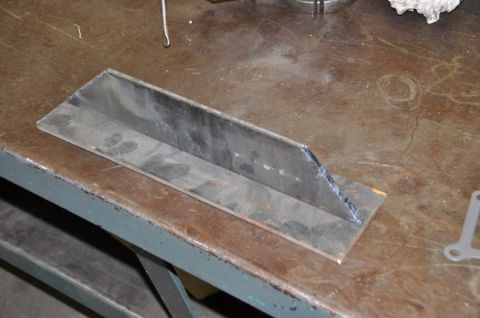 1996 Ford Bronco - A fabricated metal bracket rests on a worn workbench surface.