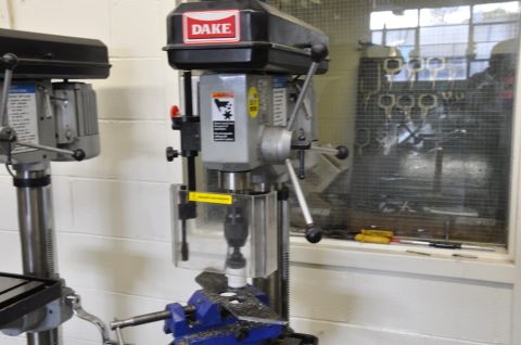 1996 Ford Bronco - A Dake drill press is shown with a blue vise holding a metal piece covered in shavings.