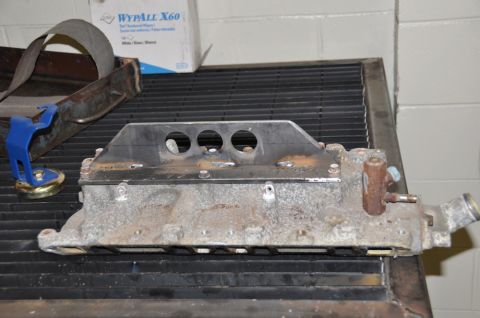1996 Ford Bronco - This is a close-up view of an engine intake manifold with a custom bracket attached, resting on a metal grate.