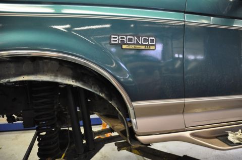 1996 Ford Bronco - Close-up of a 1996 Ford Bronco fender emblem and suspension parts.