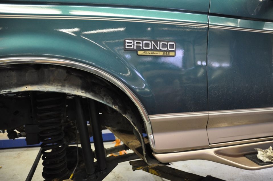 Teal Ford Bronco Eddie Bauer fender badge with wheel off on a lift