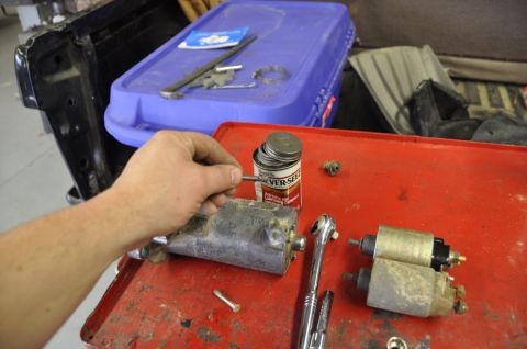 1996 Ford Bronco - A hand works on a starter solenoid next to another solenoid and tools on a workbench.