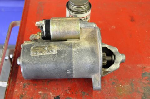 1996 Ford Bronco - A starter motor is shown on a red surface, with a can of sealant in the background.