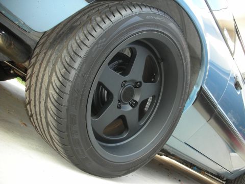 1990 Ford Mustang - A close-up shot focuses on the matte black aftermarket wheel and tire assembly of a blue vehicle.